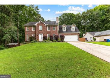 Charming two-story brick home featuring a well-manicured lawn and attached two-car garage at 435 Hampton Grn, Peachtree City, GA 30269