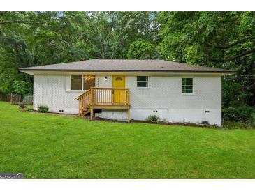 Charming home featuring a bright yellow door, grassy yard, and mature trees at 4443 Flat Shoals, Decatur, GA 30034