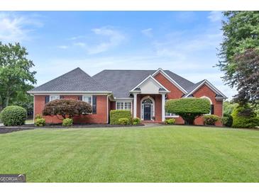 Beautiful brick home with a manicured lawn and mature landscaping at 411 Hickory Fairway Ct, Woodstock, GA 30188