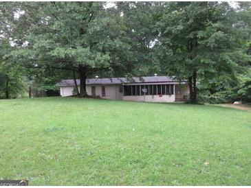 Quaint single-story home with a lush green lawn and mature trees creating a serene, private setting at 125 Highland Cir, Stockbridge, GA 30281