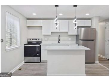 Modern kitchen featuring stainless steel appliances, white cabinets, and a kitchen island at 2106 Singer Way, Lithonia, GA 30058