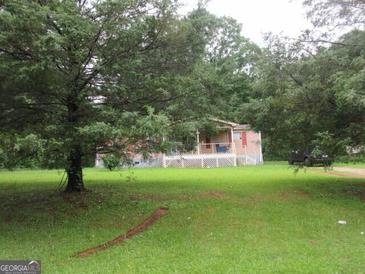 Ranch-style home with a large, grassy front yard and covered porch nestled in a woodsy setting at 280 Highland Cir, Stockbridge, GA 30281