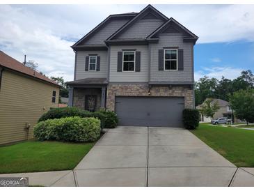 Charming two-story home featuring stone accents, gray siding, a two-car garage, and manicured landscaping at 2424 Saint Andrews Rdg, College Park, GA 30337