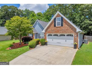Charming home featuring a well-manicured lawn, brick accents, and an attached two-car garage at 3511 Cherry Blossom Ct, Loganville, GA 30052