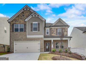 Two-story home with brick and stone accents, two-car garage, and manicured front yard at 714 Bristol Dr # 279A, Loganville, GA 30052