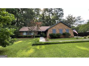 Charming brick home featuring lush green lawn, mature trees, and meticulous landscaping, radiating curb appeal at 4710 Cedar Brook Se Dr, Conyers, GA 30094