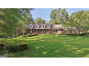 Charming brick home with a well-manicured lawn and mature trees creating a picturesque setting at 115 Shoal Creek Dr, Sharpsburg, GA 30277