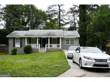 Charming grey brick home featuring a well-manicured lawn, front porch and a private driveway at 39 Mcferrin Cir, Riverdale, GA 30274