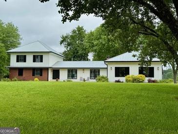 Charming home with lush green lawn, beautiful landscaping, and a metal roof at 360 Morgan Mill Rd, Brooks, GA 30205