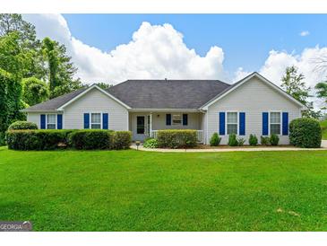 Charming single-story home with blue shutters, manicured lawn, and lush green landscaping at 227 Ferguson Ave, Locust Grove, GA 30248