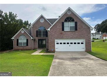 Charming two-story brick home featuring a two-car garage, well-manicured lawn, and classic curb appeal at 12189 Lauren Way, Fayetteville, GA 30215