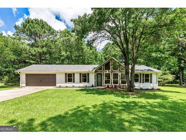 Charming single-story home featuring stone accents, a well-manicured lawn, and mature trees offering ample shade at 125 Selena Ct, Fayetteville, GA 30215