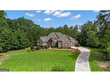 Beautiful, stone-clad home with lush lawn and driveway on a sunny day at 185 Platinum Ridge Pt, Fayetteville, GA 30215
