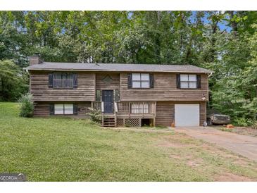 Charming split-level home with wood siding, a front porch, a garage and a lush front yard at 5804 Macedin Dr, Douglasville, GA 30135