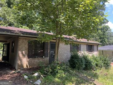 Brick home exterior featuring a mature tree in the front yard at 6337 Wellington Way, Austell, GA 30106