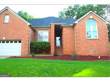 Charming all brick home featuring an attached garage and professionally landscaped yard at 122 Carolinas Way, Fayetteville, GA 30215