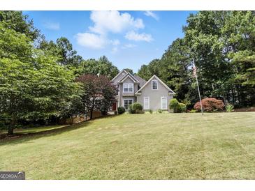 Charming two-story home with a lush lawn, mature trees and traditional architectural details at 136 Barrington Grange Dr, Sharpsburg, GA 30277