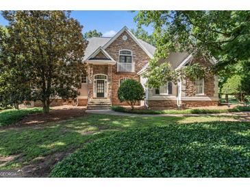 Charming stone home featuring a lush front yard with mature trees and manicured landscaping at 914 Champions Way, Mcdonough, GA 30252