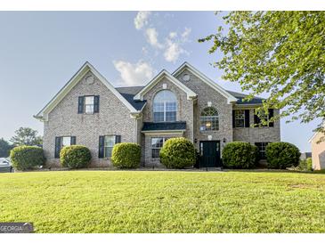 Charming brick home featuring a manicured lawn, lush landscaping, and a classic architectural design at 184 Fashion Xing, Mcdonough, GA 30252