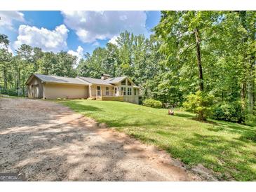 Charming one-story home with a deck and a lush, green lawn surrounded by mature trees at 351 Weldon Rd, Palmetto, GA 30268