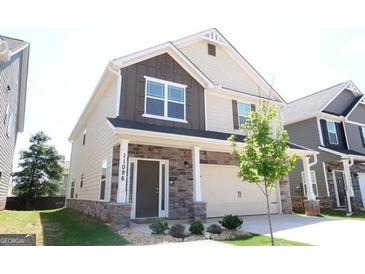 Charming two-story home featuring stone accents, brown siding, complemented by a manicured lawn, and an attached two car garage at 11096 Cornerstone Way, Hampton, GA 30228