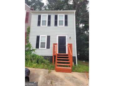 Two-story home featuring gray siding, black shutters, and a black front door with bright orange painted stairs at 2052 Charter Ln, Lithonia, GA 30058