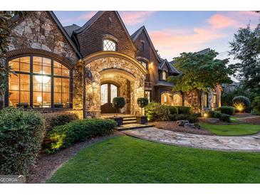 Stunning stone and brick home featuring a lush green lawn and elegant landscaping at 4874 Kettle River Pt, Suwanee, GA 30024