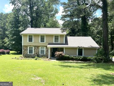 Inviting two-story home with a stone facade and well-maintained lawn, nestled in a serene, wooded setting at 3589 Burlingham Dr, Lithonia, GA 30038