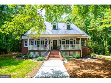 Charming exterior with metal roof, brick accents, dormers, and a welcoming porch, surrounded by lush greenery at 301 East Highway 5, Roopville, GA 30170