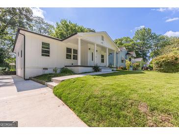 Charming renovated home featuring white exterior, inviting front porch, and lush lawn at 1446 Westmont Sw Rd, Atlanta, GA 30311