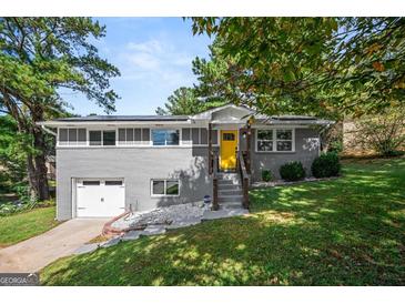 Charming gray brick home with a bright yellow front door, surrounded by a lush, green, landscaped yard at 3859 N Camp Creek Sw Pkwy, Atlanta, GA 30331