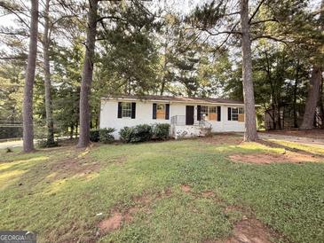 Charming one-story white home with black shutters and a well-maintained front yard with mature shade trees at 10103 Allen Sw Dr, Covington, GA 30014