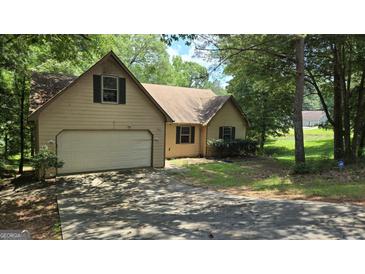 Charming home featuring an attached garage, mature trees and front yard at 1448 Se Hillside Place, Conyers, GA 30094