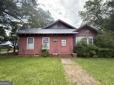 Exterior view of a single-story home with a metal roof, red siding, and a small, well-maintained front yard at 301 Wedowee St, Bowdon, GA 30108