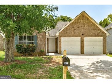 Charming brick home featuring a two-car garage and well-maintained front yard at 1735 Deer Crossing Cir, Jonesboro, GA 30236