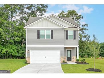 Charming two-story home with gray siding, a white garage door, and a well-manicured lawn at 282 Limestone Circle, Conyers, GA 30013