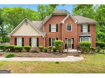 Charming brick home featuring black shutters, complemented by lush landscaping and mature trees at 10044 Point View Dr, Jonesboro, GA 30238