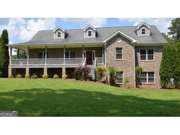 Charming brick home featuring a covered porch, dormer windows, and a well-maintained lawn at 195 Twin Oaks Dr, Hampton, GA 30228
