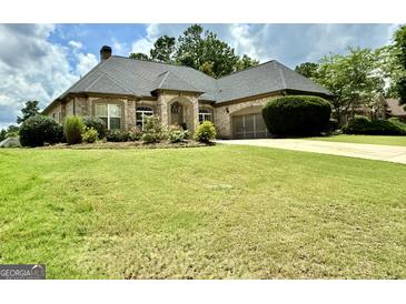 Beautiful brick home features a well-manicured lawn and a spacious driveway leading to an attached two-car garage at 6409 Caledon Ct, Locust Grove, GA 30248