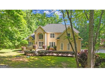Elegant stucco home with manicured landscaping and a lush, green lawn surrounded by mature trees at 551 Lees Mill Rd, Fayetteville, GA 30214