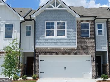 Two-story townhome features a two-car garage, blue shingle siding, and brick accents at 332 Sinclair Ct # 77, Mcdonough, GA 30253