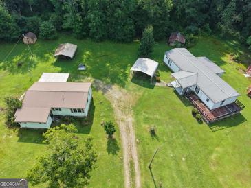 A beautiful aerial view of a farmhouse with a metal roof surrounded by lush greenery at 323 Hollonville Rd, Brooks, GA 30205