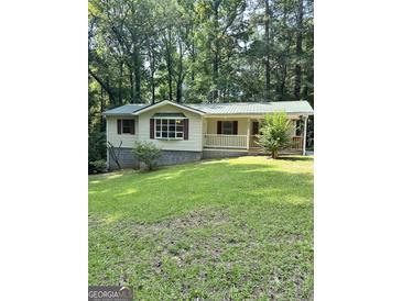 Charming home featuring a covered porch, green metal roof, and mature trees surrounding the property at 4688 Brice Dr, Union City, GA 30291