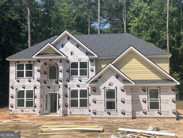 New two-story home with yellow siding, a grey roof, and large windows in a wooded lot at 5565 Hwy 155, Stockbridge, GA 30281