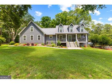 Charming gray home features a meticulously manicured lawn, colorful flowerbeds, and dormer windows at 152 Bear Creek Rd, Moreland, GA 30259