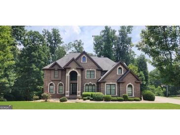 Inviting brick home featuring manicured landscaping, arched windows and an impressive entryway at 8260 Equinox Ln, Fairburn, GA 30213