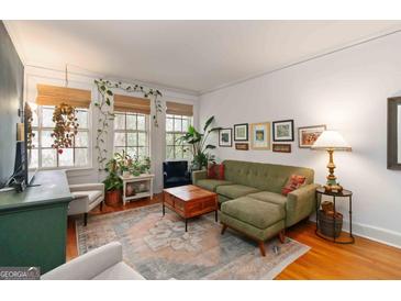 Bright living room with an olive sofa, hardwood floors, and lush green plants at 1166 Virginia Avenue Northeast Ne Ave # 8, Atlanta, GA 30306