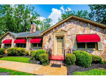 Charming stone home with red awnings and well-manicured landscaping provides great curb appeal at 508 College St, Bowdon, GA 30108