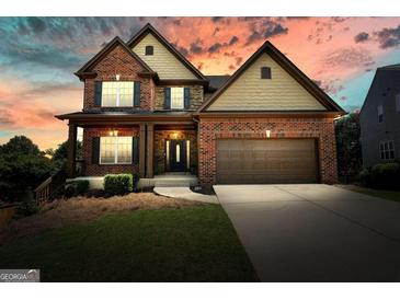 Charming two-story brick home with a covered front porch and manicured lawn at sunset at 6665 Flagstone Ct # 918, Cumming, GA 30028