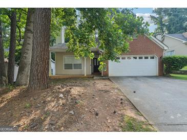 Charming home with a two-car garage and partially obscured by mature trees at 686 Shore Ln, Lithonia, GA 30058